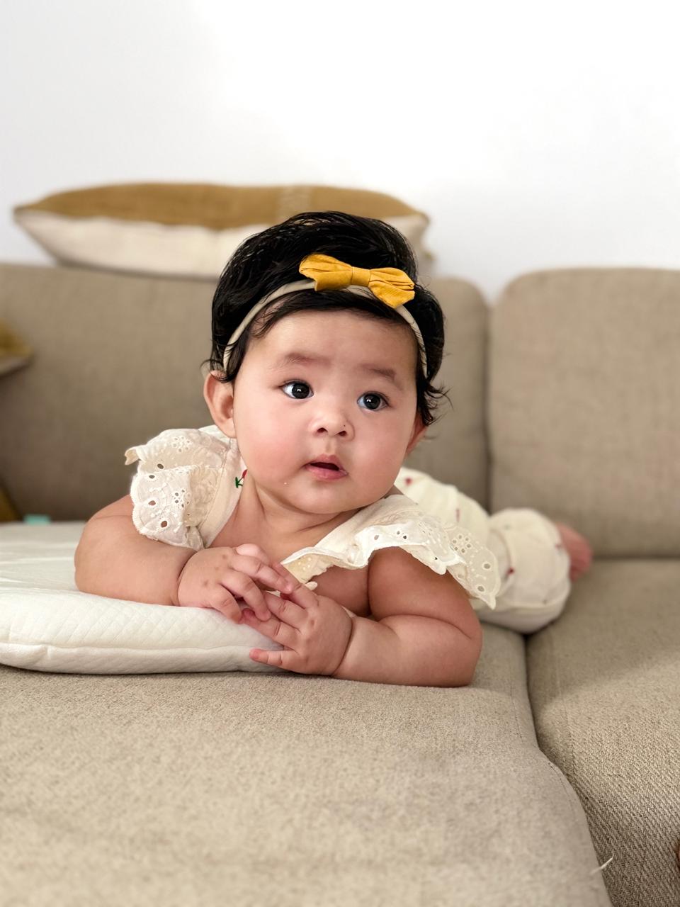 Lucia wearing a yellow bow and a cream outfit